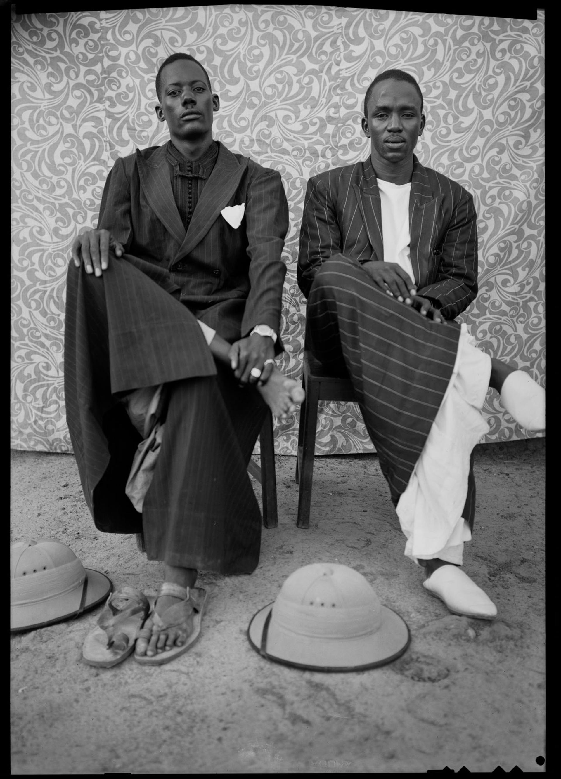 Black-and-white photograph of two seated men in striped suits