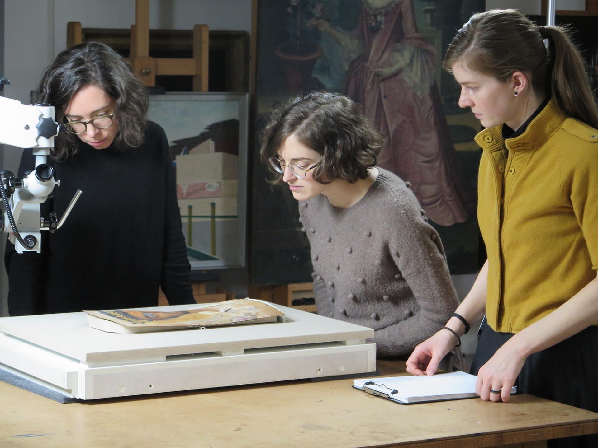 Three people examine an object in the Brooklyn Museum's Conservation department