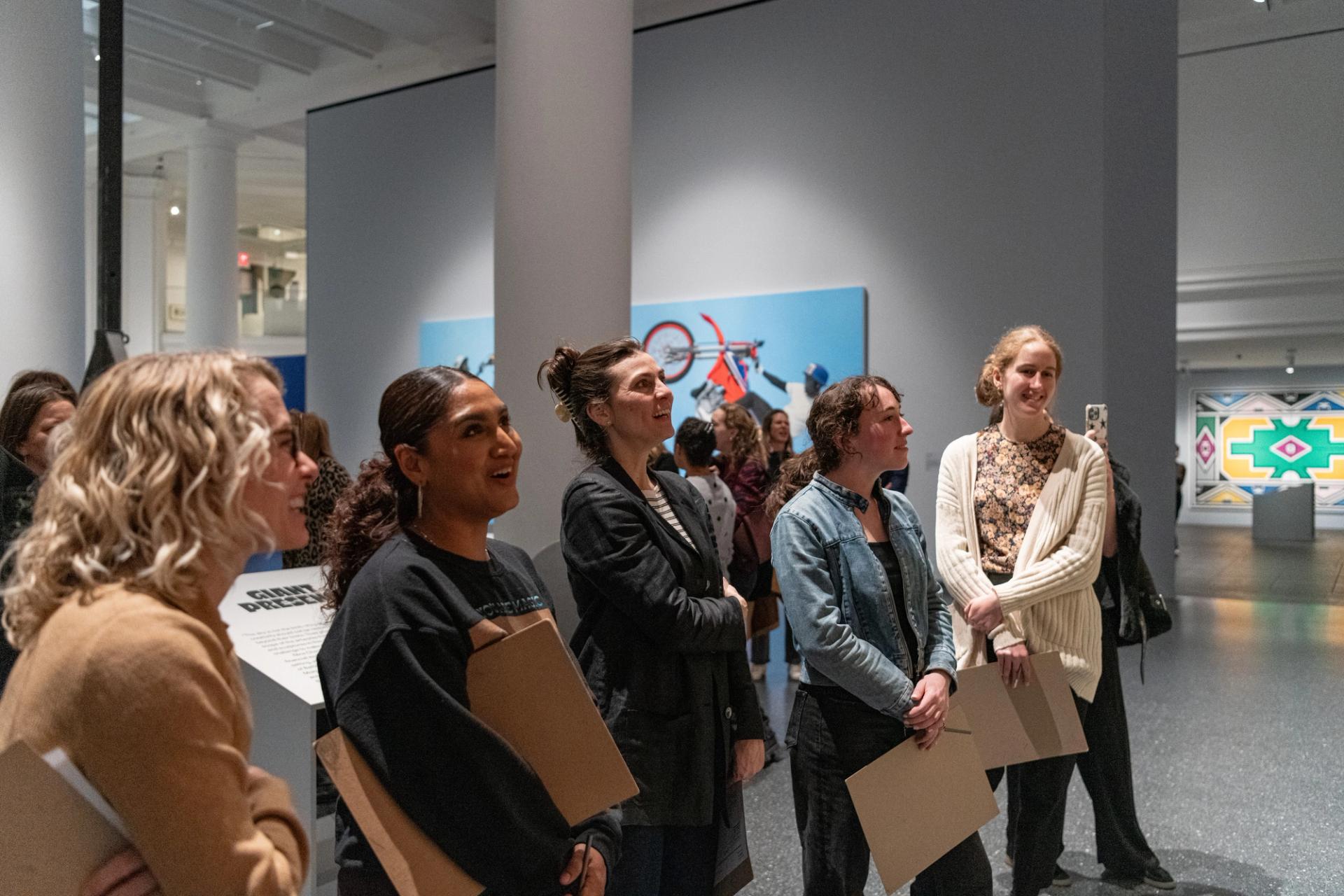 A group of five educators are smilling and talking to each other while looking at an artwork that is out of frame