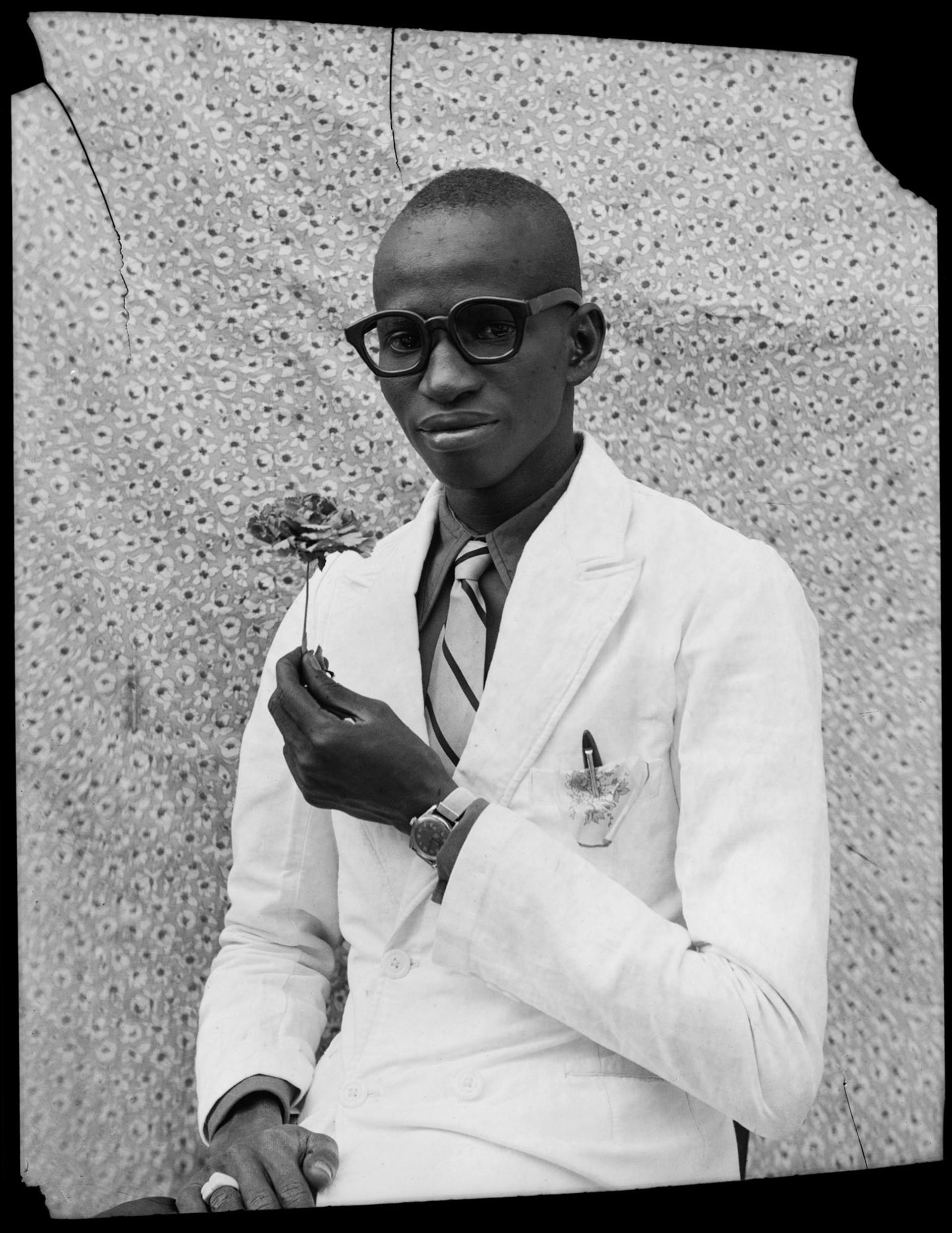 Black-and-white photograph of a person in a white coat holding a flower