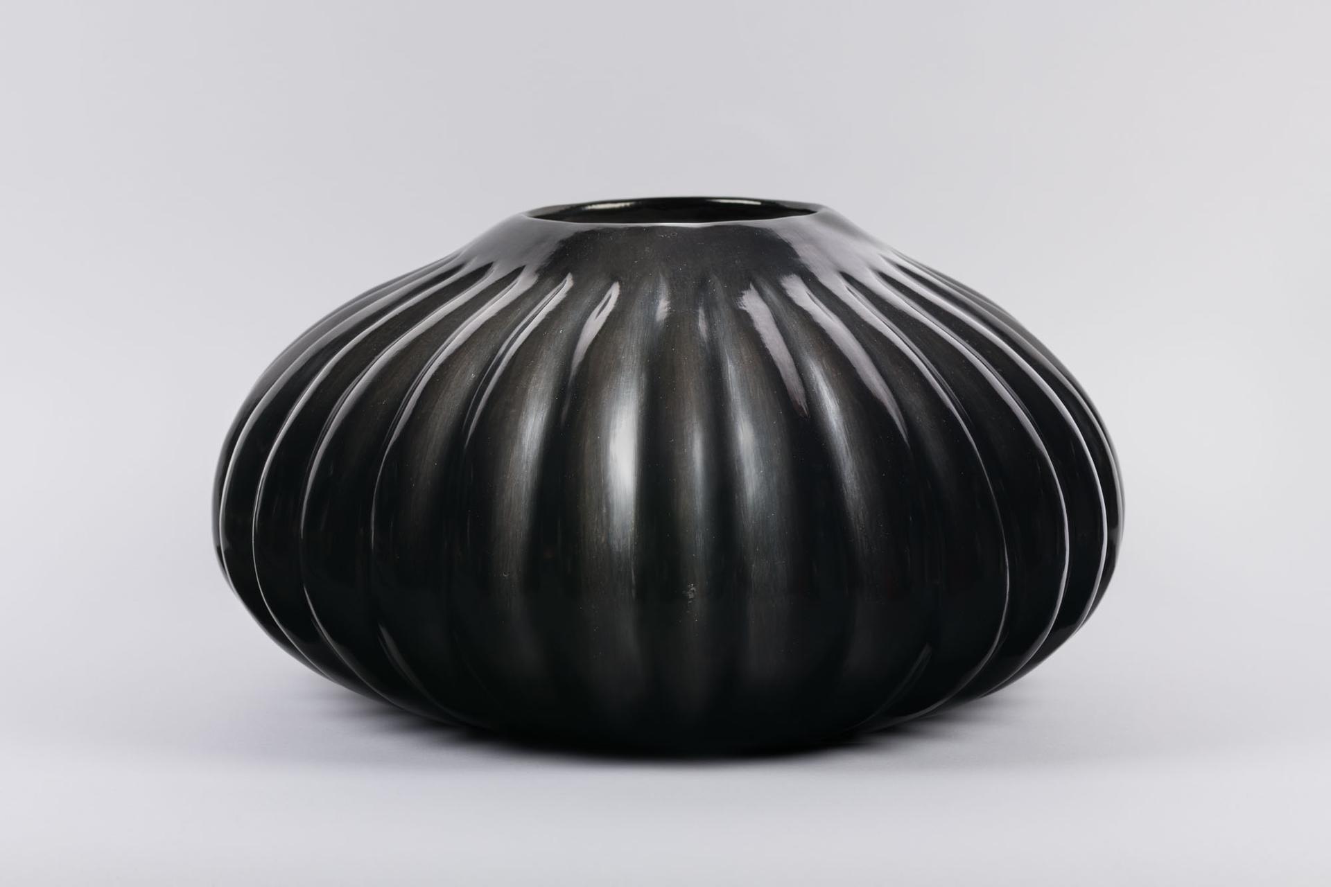 Photo of a black vase with vertical lines radiating acrossed it