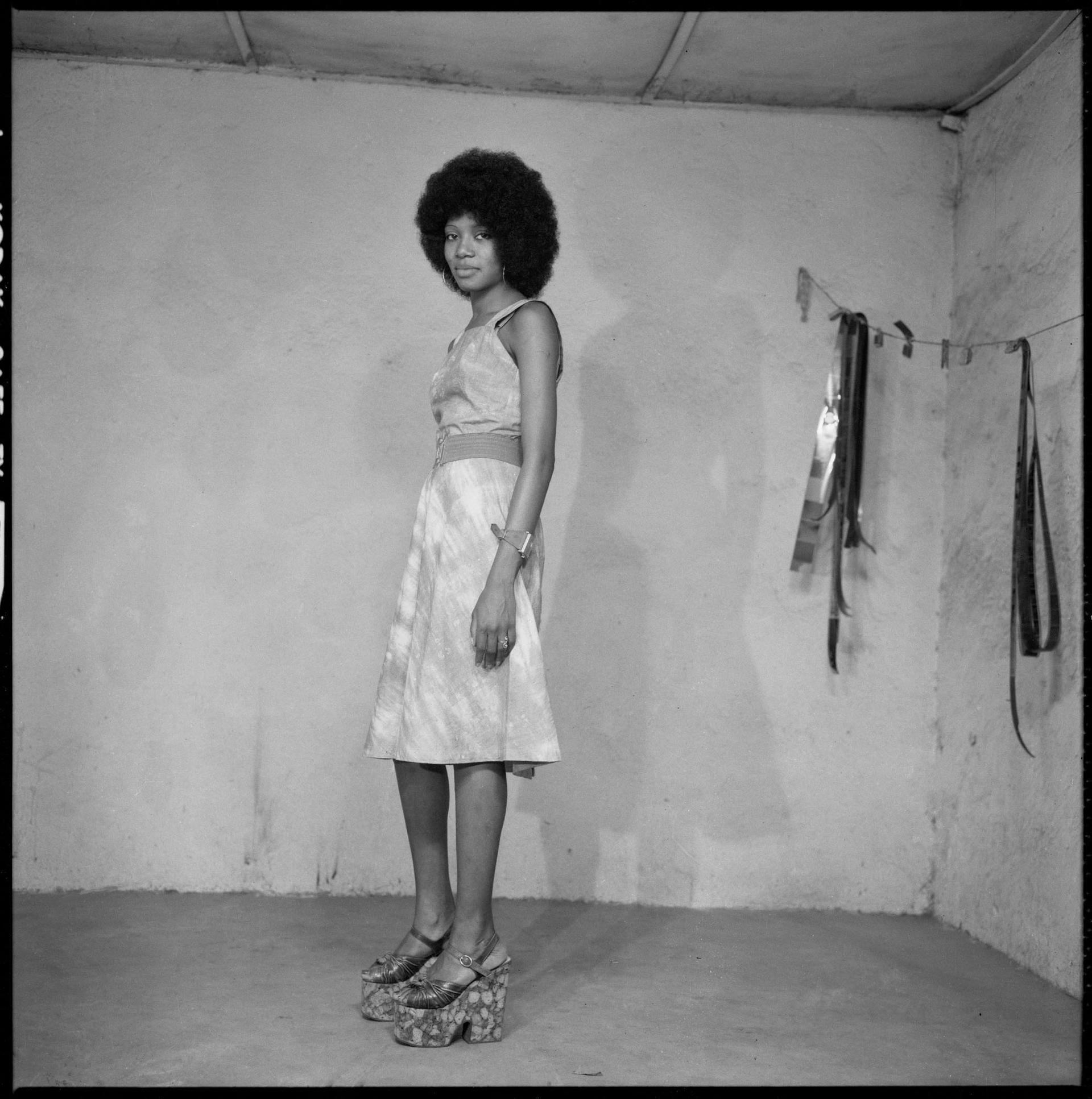 Black-and-white photograph of a woman in a dress and platform shoes